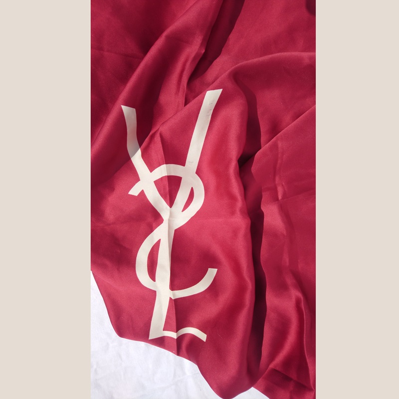 Foulard en soie rouge et beige signé du couturier Français Yves Saint Laurent - Red and beige silk scarf signed by the French designer Yves Saint Laurent. Foulard en soie rouge et beige signé du couturier Français Yves Saint Laurent - Red and beige silk scarf signed by the French designer Yves Saint Laurent.